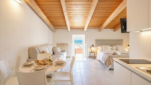Ein modernes Interieur mit Holzbalkendecke, einem Essbereich mit Tisch für zwei Personen, einer Couch und einem Bett mit Blick.