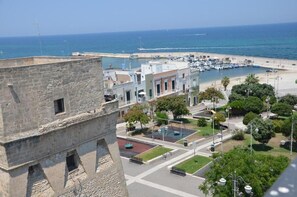A coastal town with a historic stone building, a marina, and a beach. - Palazzo dela Torre (Bari)