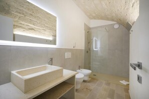 A modern bathroom with a large freestanding bathtub, a glass-enclosed shower, and a toilet. - Palazzo dela Torre (Bari)