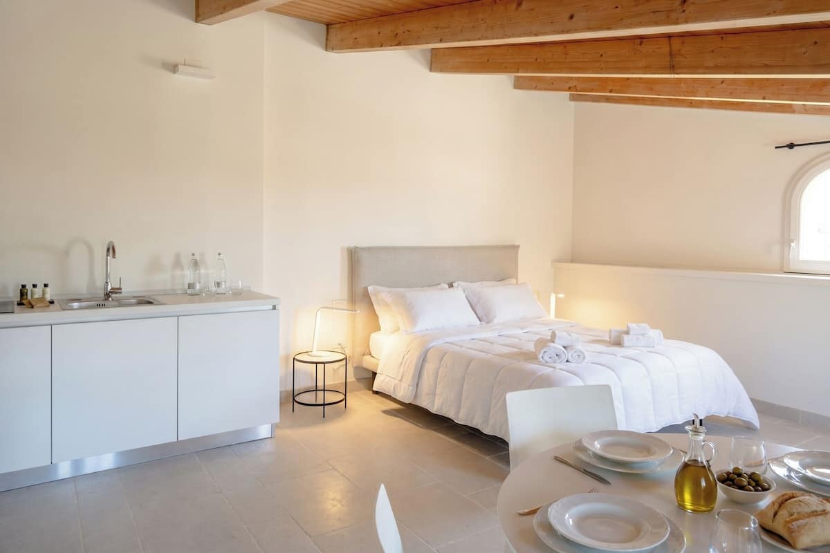 Une chambre à coucher moderne avec un lit, une table de chevet et une petite table ronde sur laquelle se trouve une lampe.