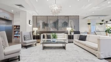 A modern living room with a white sofa, armchairs, a coffee table, and a decorative wall panel.