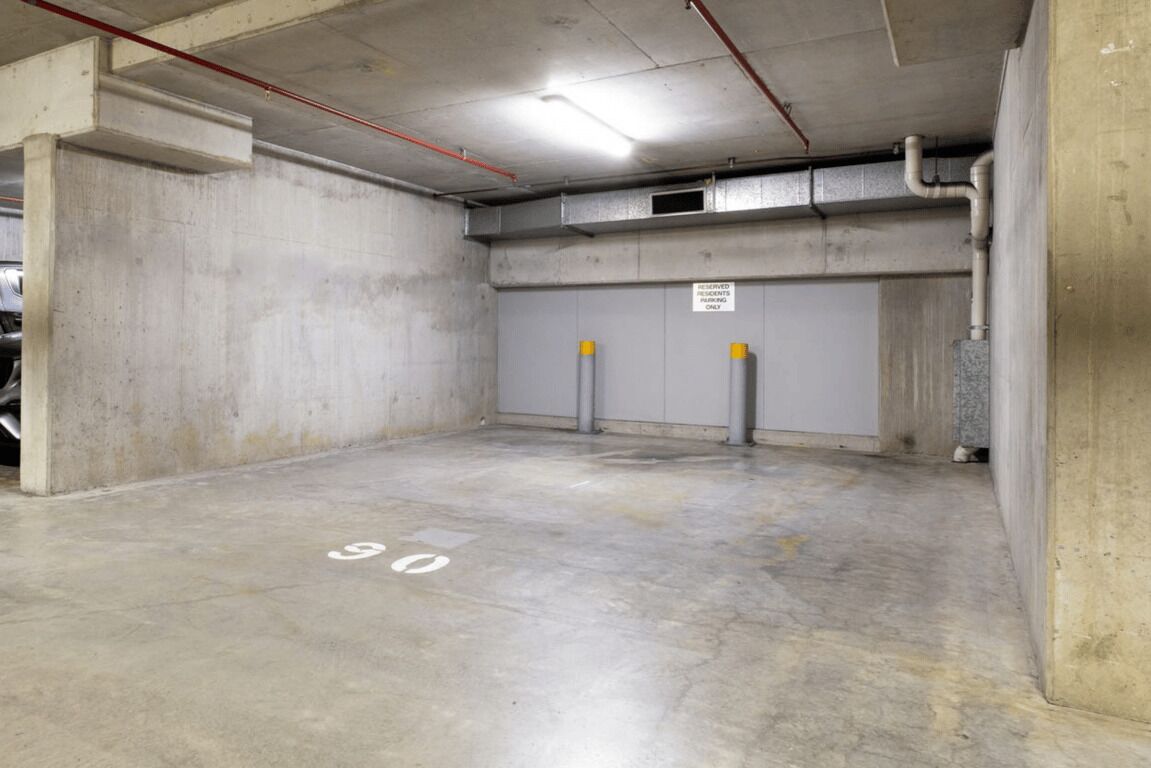 A parking garage with concrete walls, a flat floor marked with numbers, and a sign indicating reserved parking.