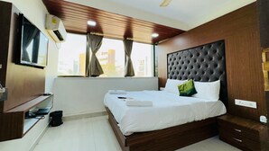 A modern hotel room with a large bed, a ceiling fan, a TV mounted on the wall, and a window with curtains. - artus inn midc andheri east mumbai (Mumbai)