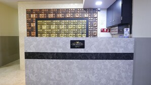 A reception desk with a marble design, a sign for New Artus Inn, and a wall with a brick pattern. - artus inn midc andheri east mumbai (Mumbai)