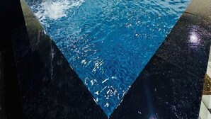 An indoor swimming pool with clear water, a black marble edge, and a tiled border. - Hotel Vanvira (Mawal)