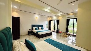 A modern hotel room with a large bed, a separate seating area, and a balcony with a view. - Hotel Vanvira (Mawal)