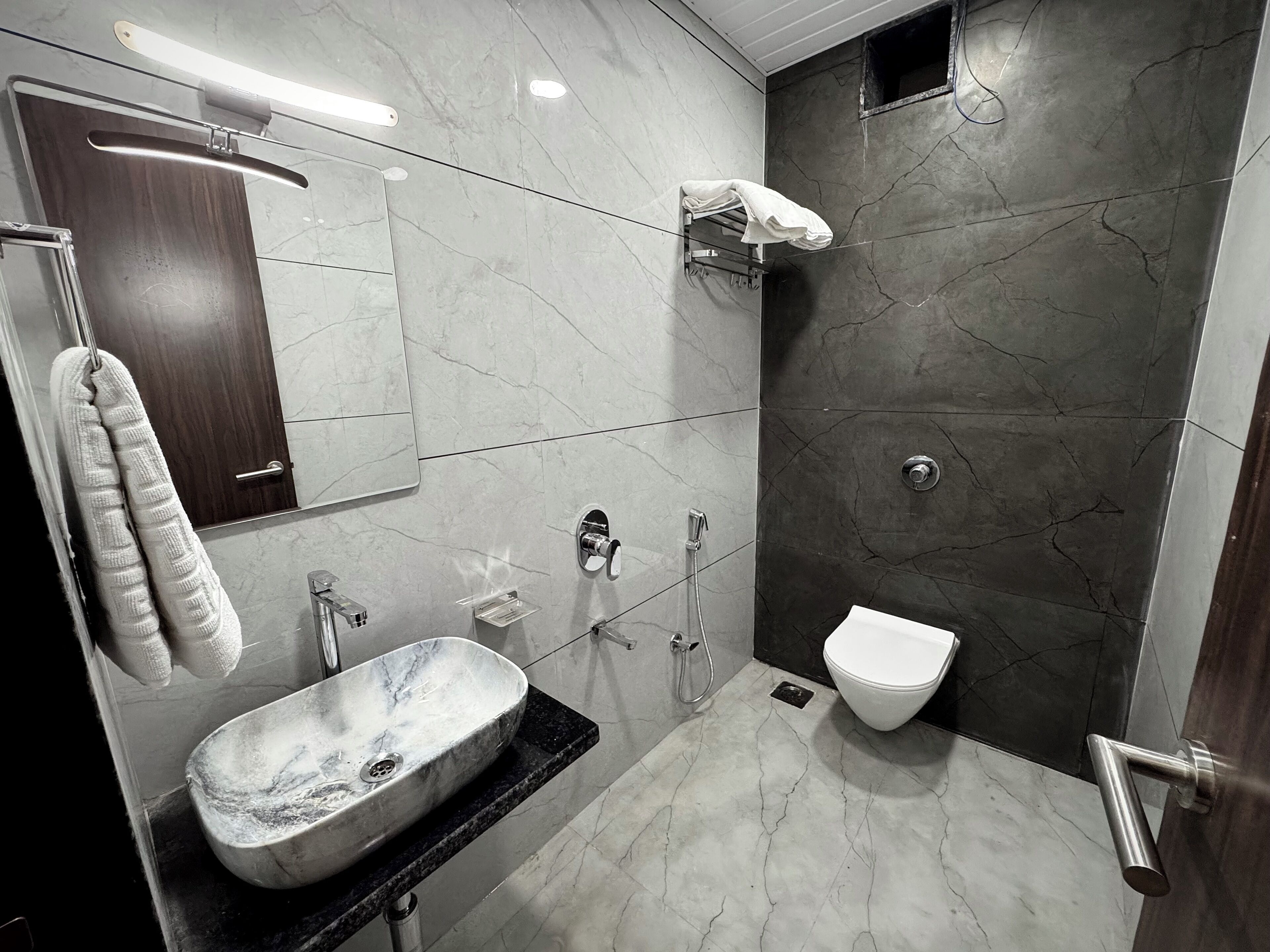 Een moderne badkamer met een marmeren wastafel, toilet en douche.