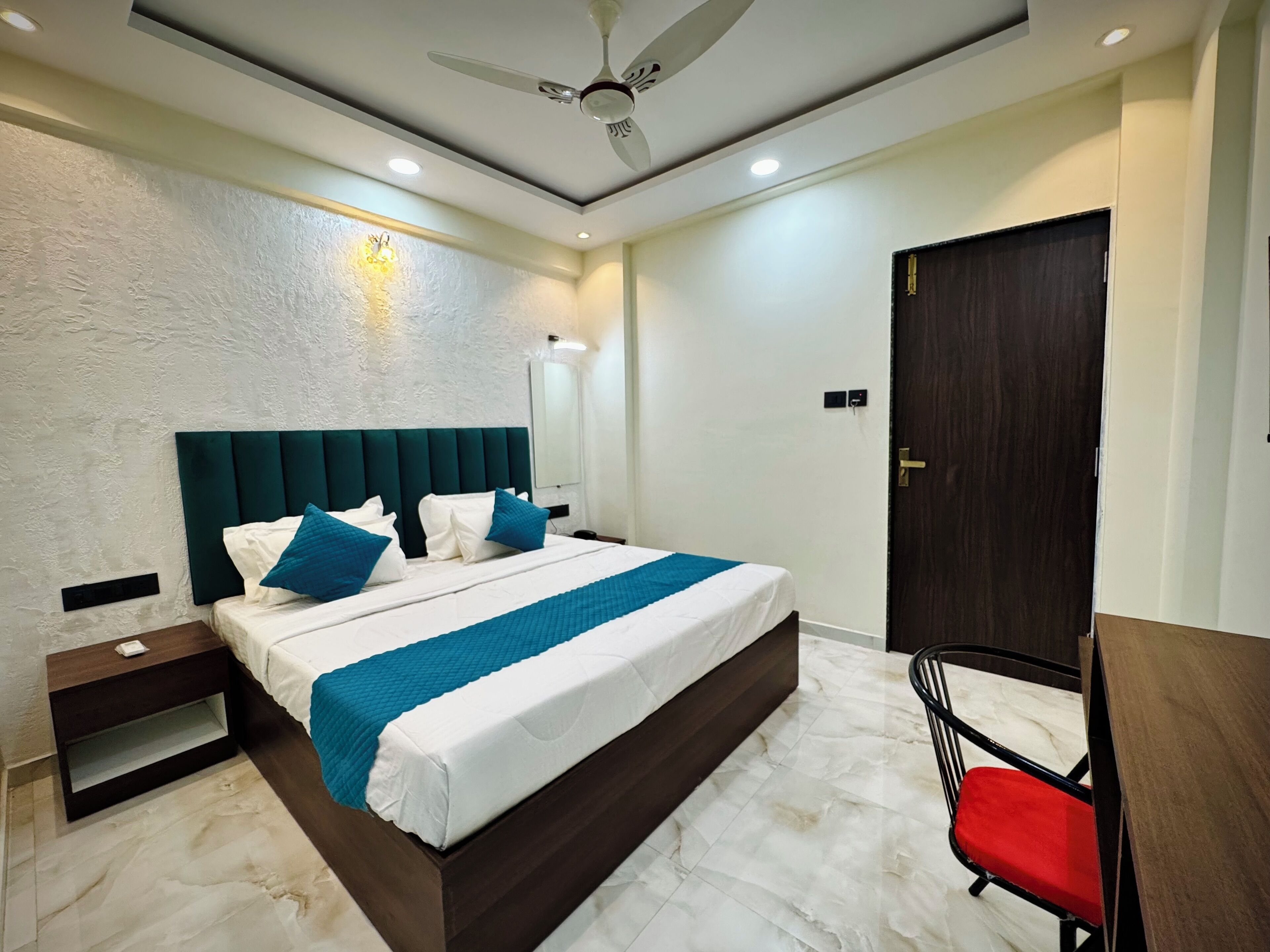 A modern bedroom with a large bed, a nightstand, a chair, and a door.