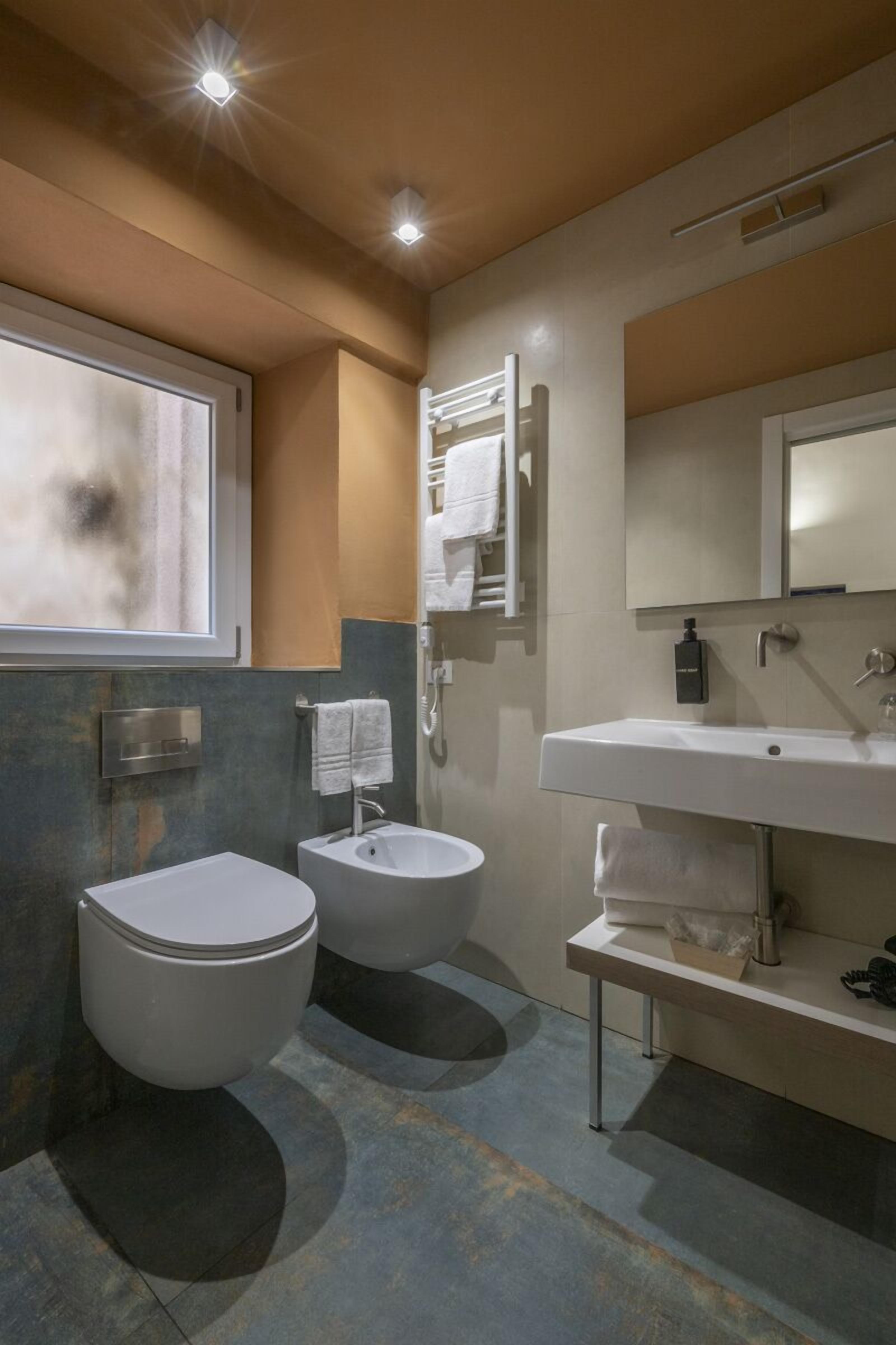 A modern bathroom with a toilet, bidet, and sink.