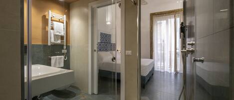 A modern bathroom with a glass-enclosed shower, a large bathtub, and a separate sink area.