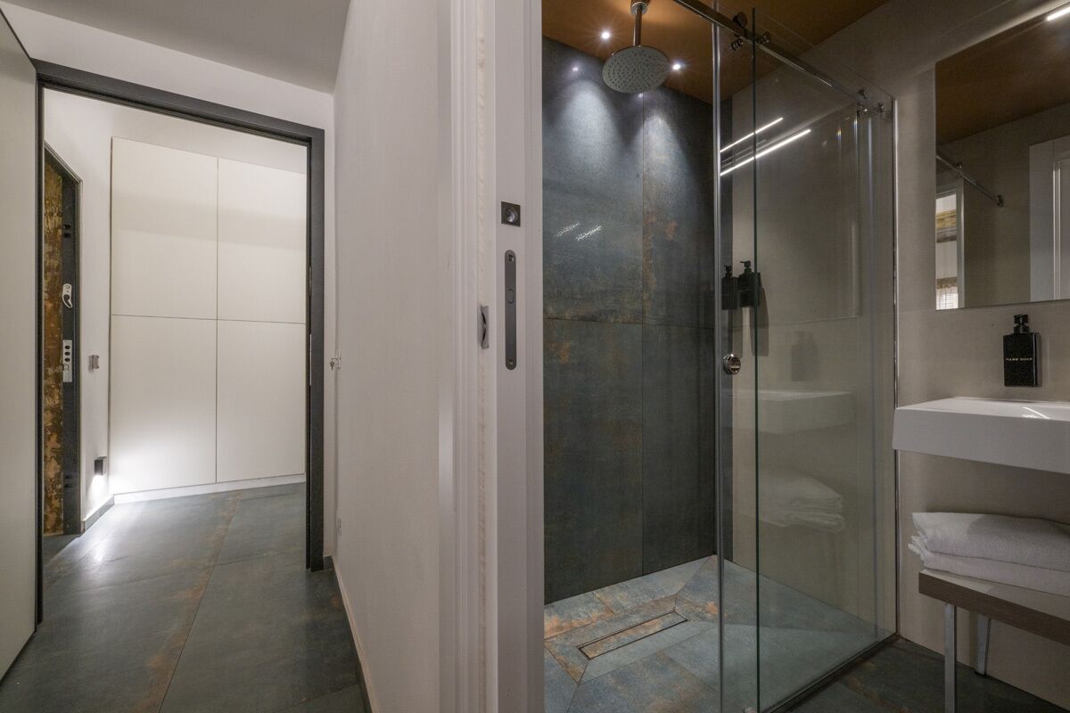 Bany modern amb plat de dutxa de vidre, un lavabo blanc i un mirall.