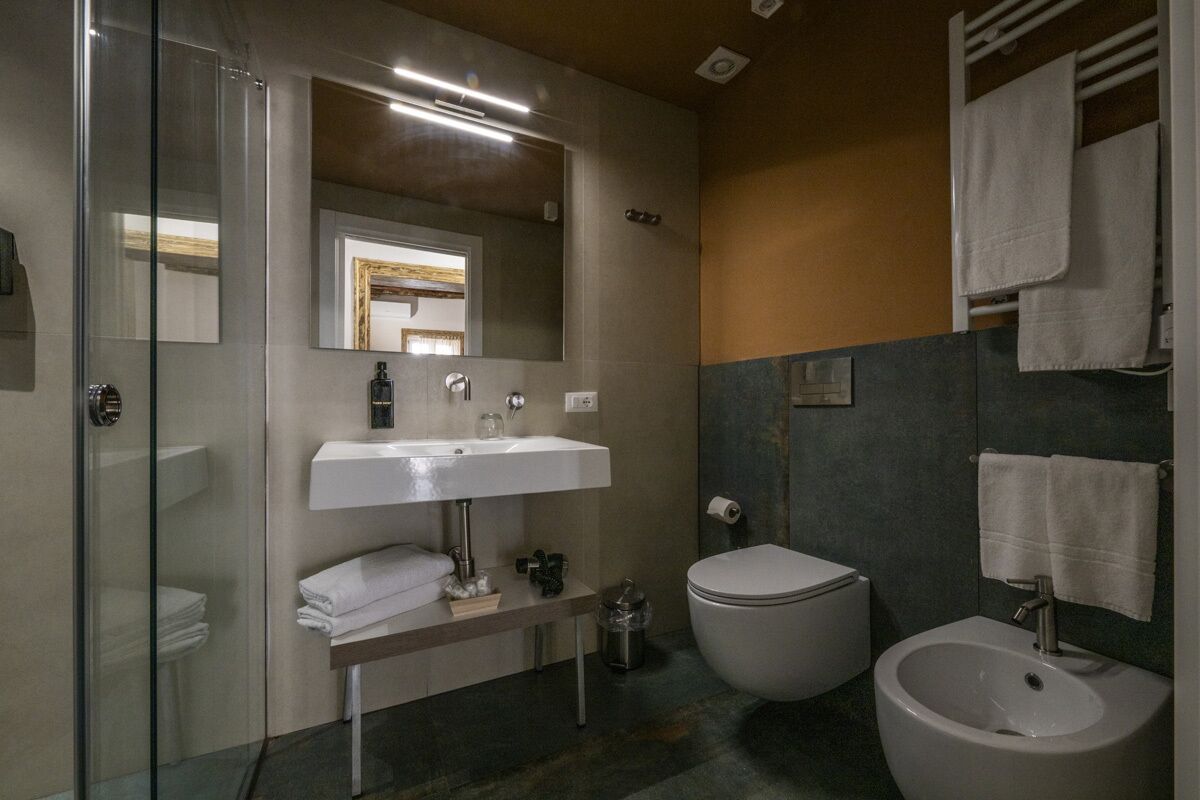 Un baño moderno con cabina de ducha de vidrio, un lavamanos blanco, un inodoro y un bidé.