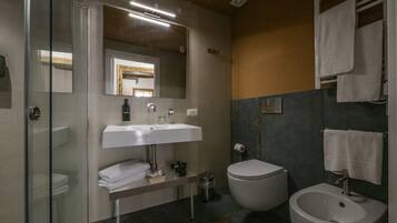 Un baño moderno con cabina de ducha de vidrio, un lavamanos blanco, un inodoro y un bidé.