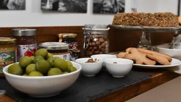 Una mesa con diversos alimentos, incluyendo aceitunas, frascos de conservas y pan.