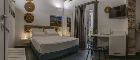A bedroom with a bed, bedside tables, a desk, a TV, and a window with curtains.