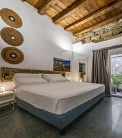A bedroom with a wooden ceiling, a bed, a nightstand, a mirror, and a window with curtains.