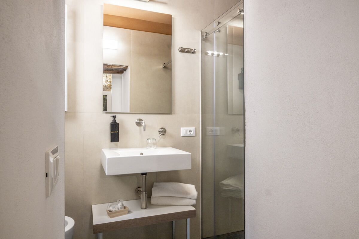 A modern bathroom with a white sink, mirror, and glass shower enclosure.