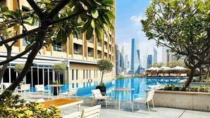 A rooftop pool area with outdoor seating and a view of the city skyline.
