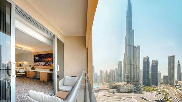 A modern hotel room with a balcony, a dining area, and a view of the Burj Khalifa.