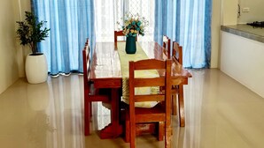 A dining area with a wooden table and chairs, a vase of flowers, and a potted plant. - Enjoyable 4-bedroom house with AC in Panglao (Panglao)