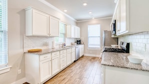 A kitchen with white cabinets, granite countertops, a stove, and a dishwasher.