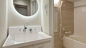 A modern bathroom with a round mirror, a white sink, and a shower area.