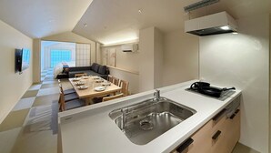 A modern kitchen with a large island, a dining area with a checkered floor, and a view of a cityscape through a sliding door.