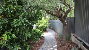 Ein schmaler Ziegelweg, gesäumt von dichtem Grün und einem Holzzaun.