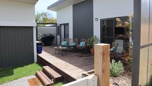 Eine moderne Terrassengestaltung im Freien mit Holzdeck, Gartenmöbeln und einem Grill.