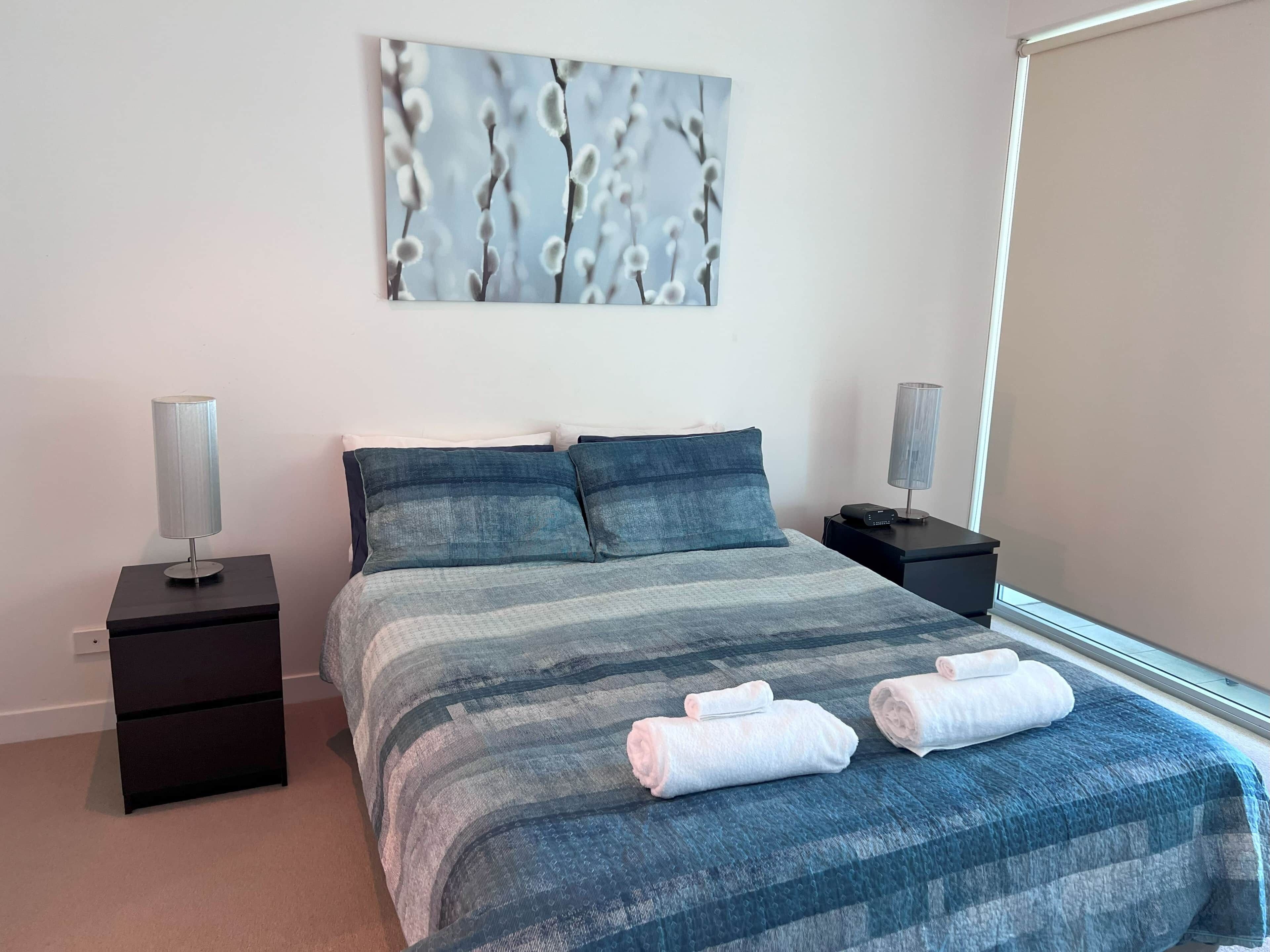 A neatly arranged bedroom with a bed, two bedside tables, a wall-mounted lamp, and a window.