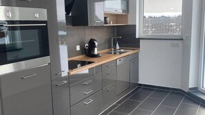 A modern kitchen with stainless steel appliances, a wooden countertop, and a window with a view. - Cozy vacation home (Biessenhofen)