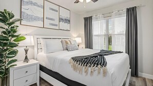 Un dormitorio con cama, mesita de noche, lámpara y ventilador de techo.