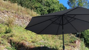 A patio with a stone wall, a table with two chairs, and a large umbrella. - Vacation apartment "Beim alten Pfarrhaus" (Zell (Mosel))