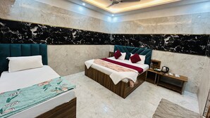 Une chambre d’hôtel moderne avec un grand lit, un lit plus petit, des murs en marbre et un ventilateur de plafond.
