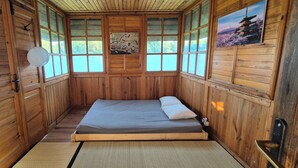 Een houten kamer met een bed, een ventilator en een afbeelding van een pagode.