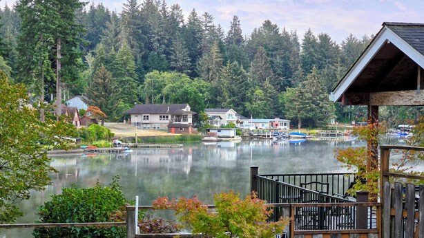 A lakeside property with a dock, wooden fence, and a bird sculpture.