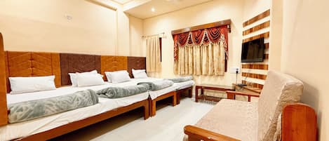 A hotel room with a large bed, a sofa, a TV, and a ceiling fan.