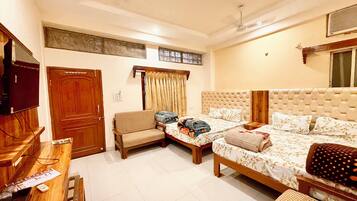 A bedroom with two beds, a television, a wooden door, and a window with curtains.