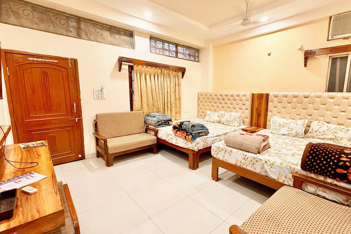 A hotel room with a bed, two bedside tables, a sofa, a chair, a desk, and a television.