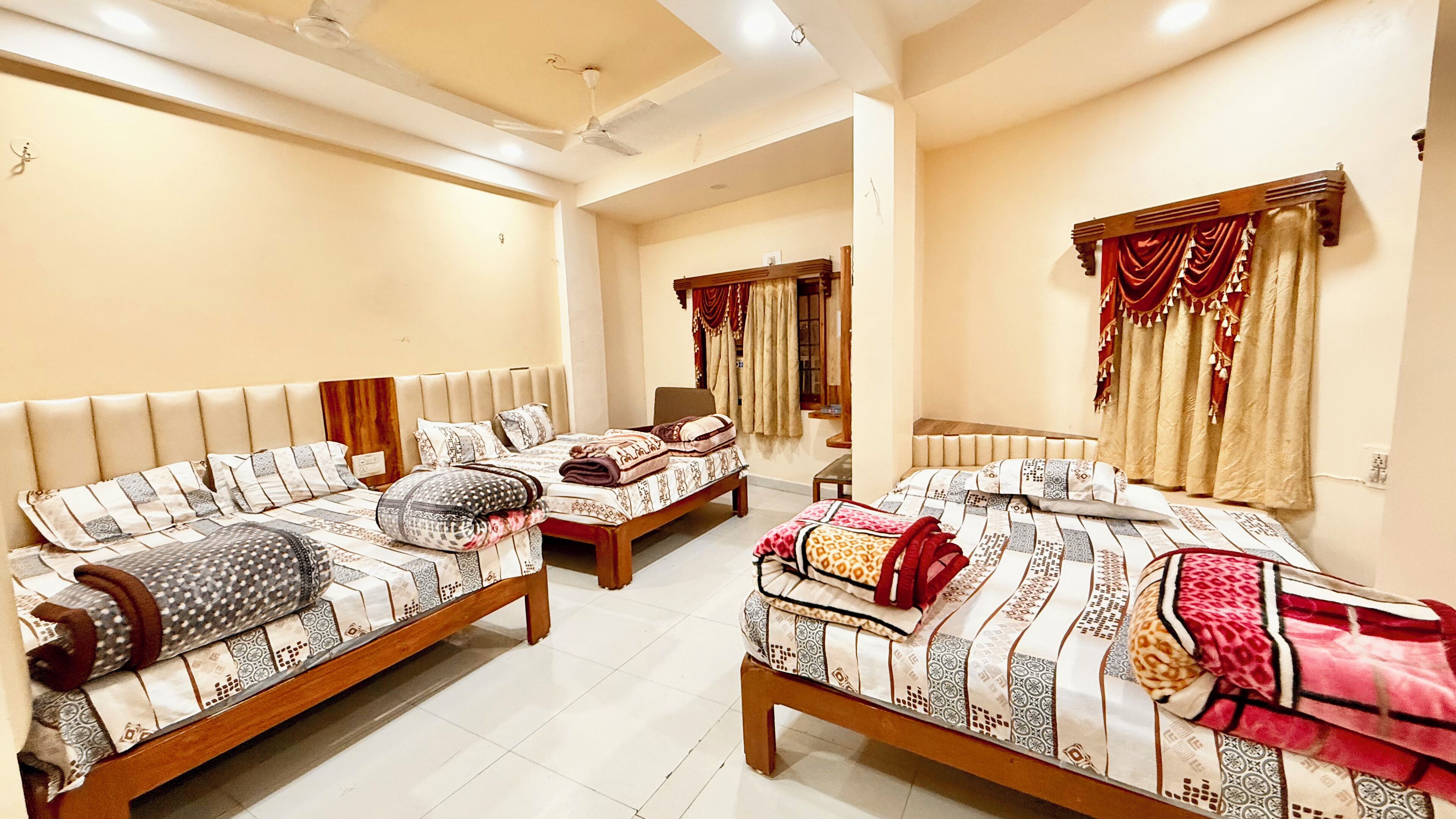 A hotel room with three beds, a ceiling fan, and a large mirror.