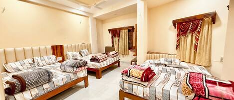 A hotel room with three beds, a ceiling fan, and a large mirror.