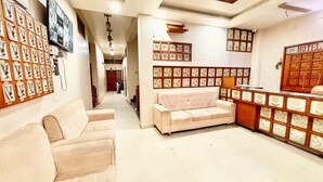 Eine Hotelhalle mit einer Rezeption, einer Couch und einer Wand mit gerahmten Bildern.