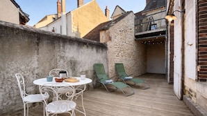 Eine Terrasse mit Tisch und Stühlen, ein Holzdeck und eine Steinmauer.