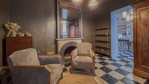Una sala de estar con chimenea, dos sillones, un tapete y suelo a cuadros.