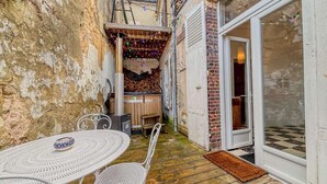 Un patio con una mesa redonda y sillas, una sauna y un banco de madera.