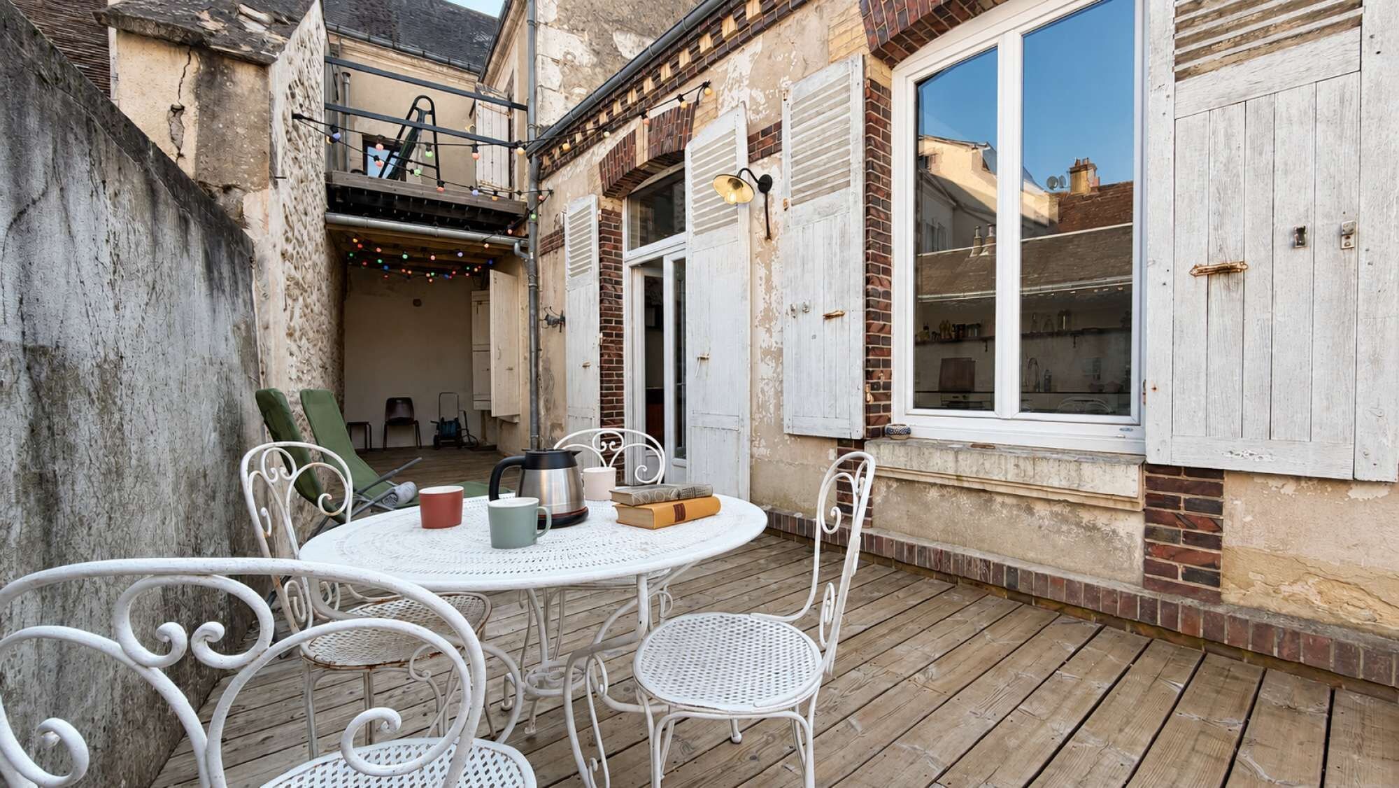 Table et chaises sur la terrasse, devant la façade de la maison. Un coin agréable pour un café, une lecture ou un moment partagé en extérieur.