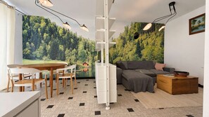 Una sala de estar moderna con comedor, un sofá, una mesa de centro y un cuadro en la pared.
