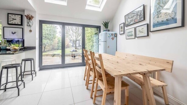 Una cocina moderna con una mesa de comedor de madera, taburetes negros y un ventanal grande.