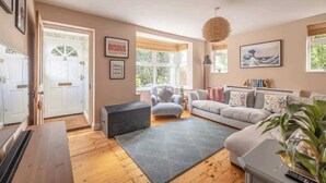 Una sala de estar con sofá, alfombra, sillón y puerta que da al exterior.