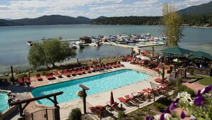 A resort with a swimming pool, lounge chairs, and a dock area. - Live the Lodge Life | Luxe Home Near Trails, Lake & Spa Amenities (Whitefish)